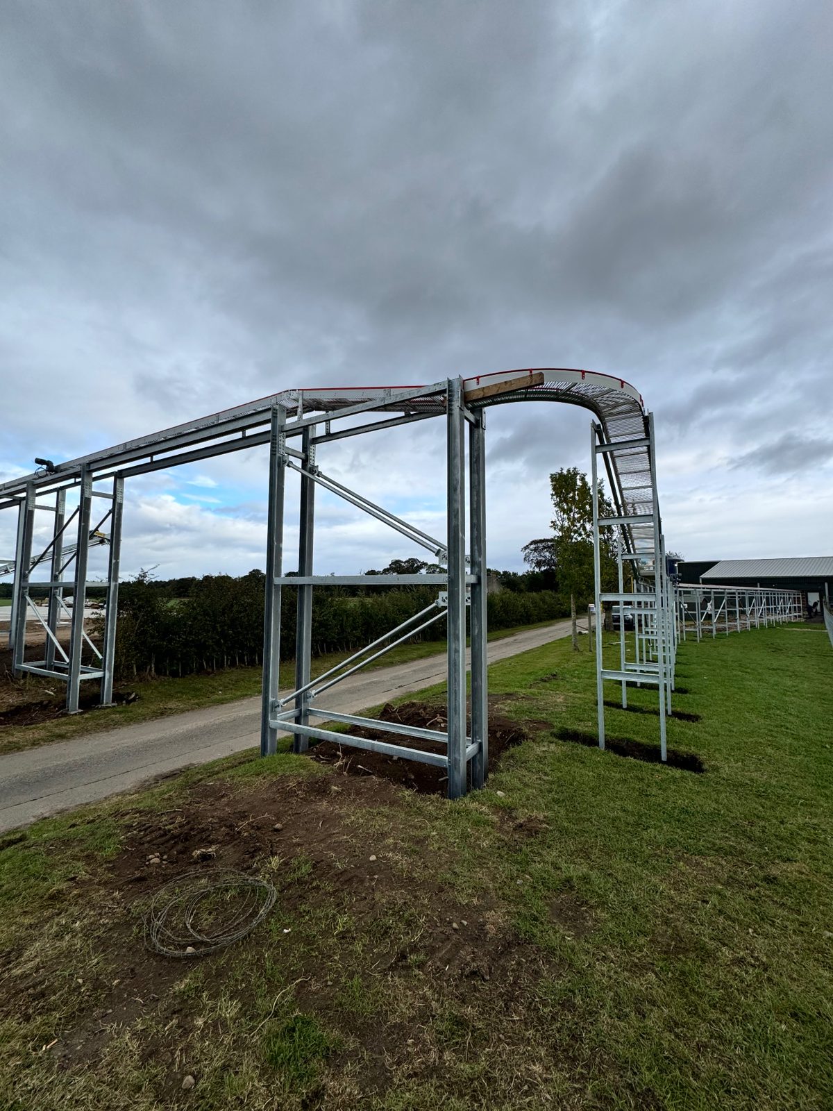 Elevated egg conveyor support structure bridging the articulated lorry route