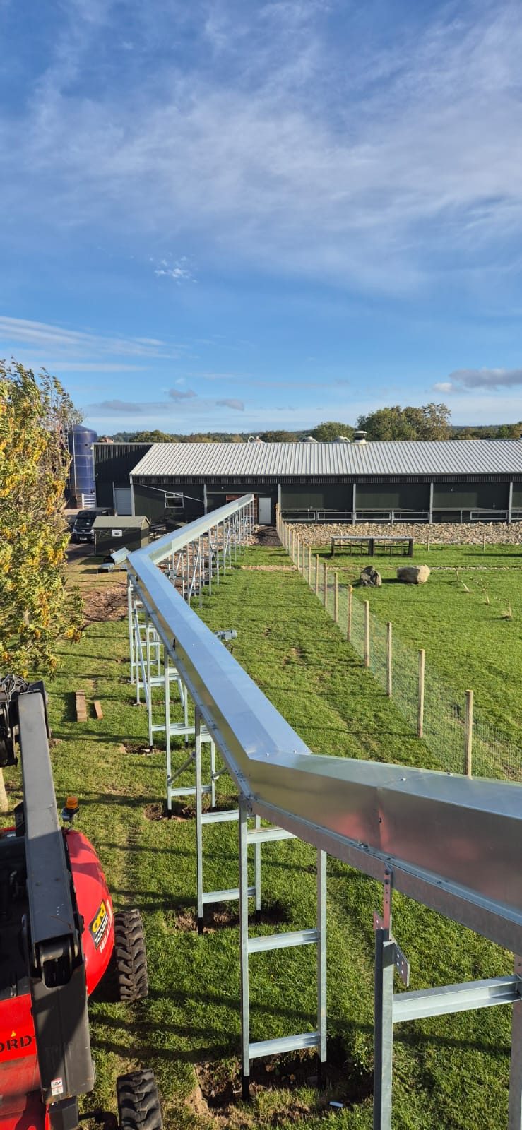 Elevated covered egg conveyor running between agricultural buildings