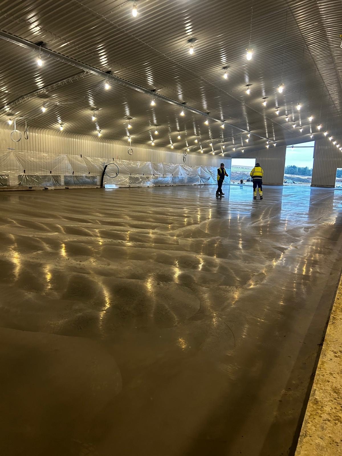 Polished internal concrete floor of the completed poultry unit with lighting reflecting off the surface