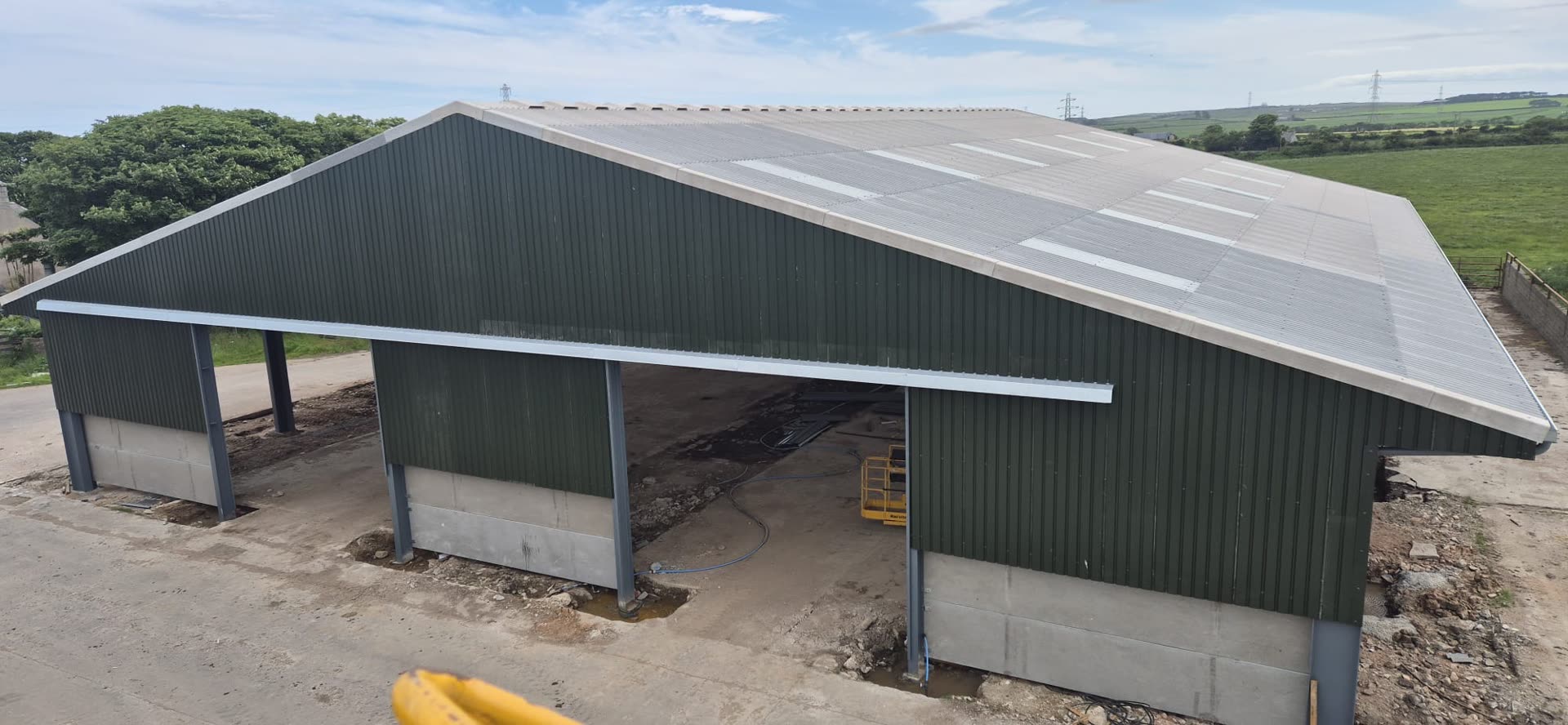 Green wall cladding and roof sheeting being fitted to an RPD steel-framed farm building