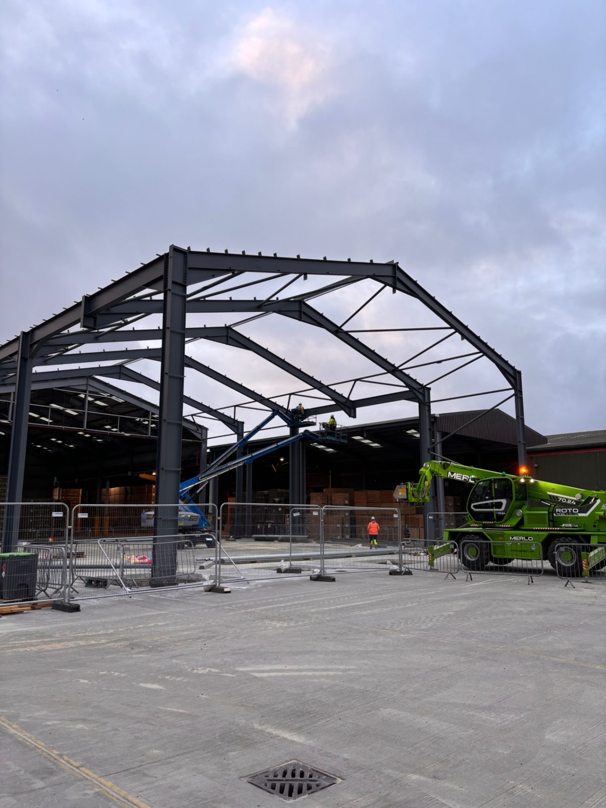 Canopy steel frame at dusk with a telehandler positioned alongside