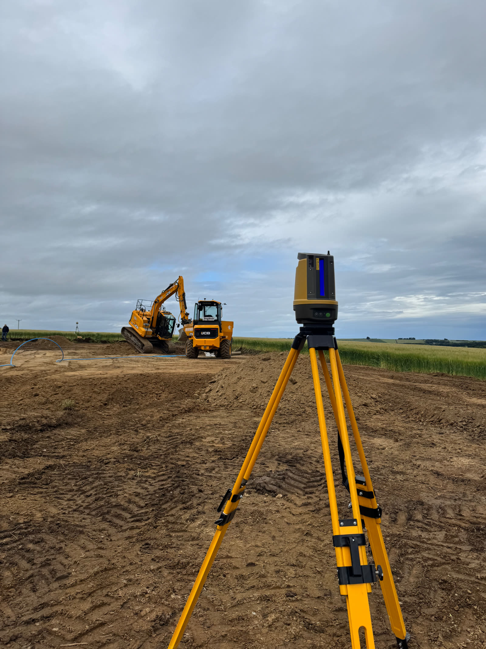 Topcon total station set up on an RPD earthworks site with a JCB excavator working behind