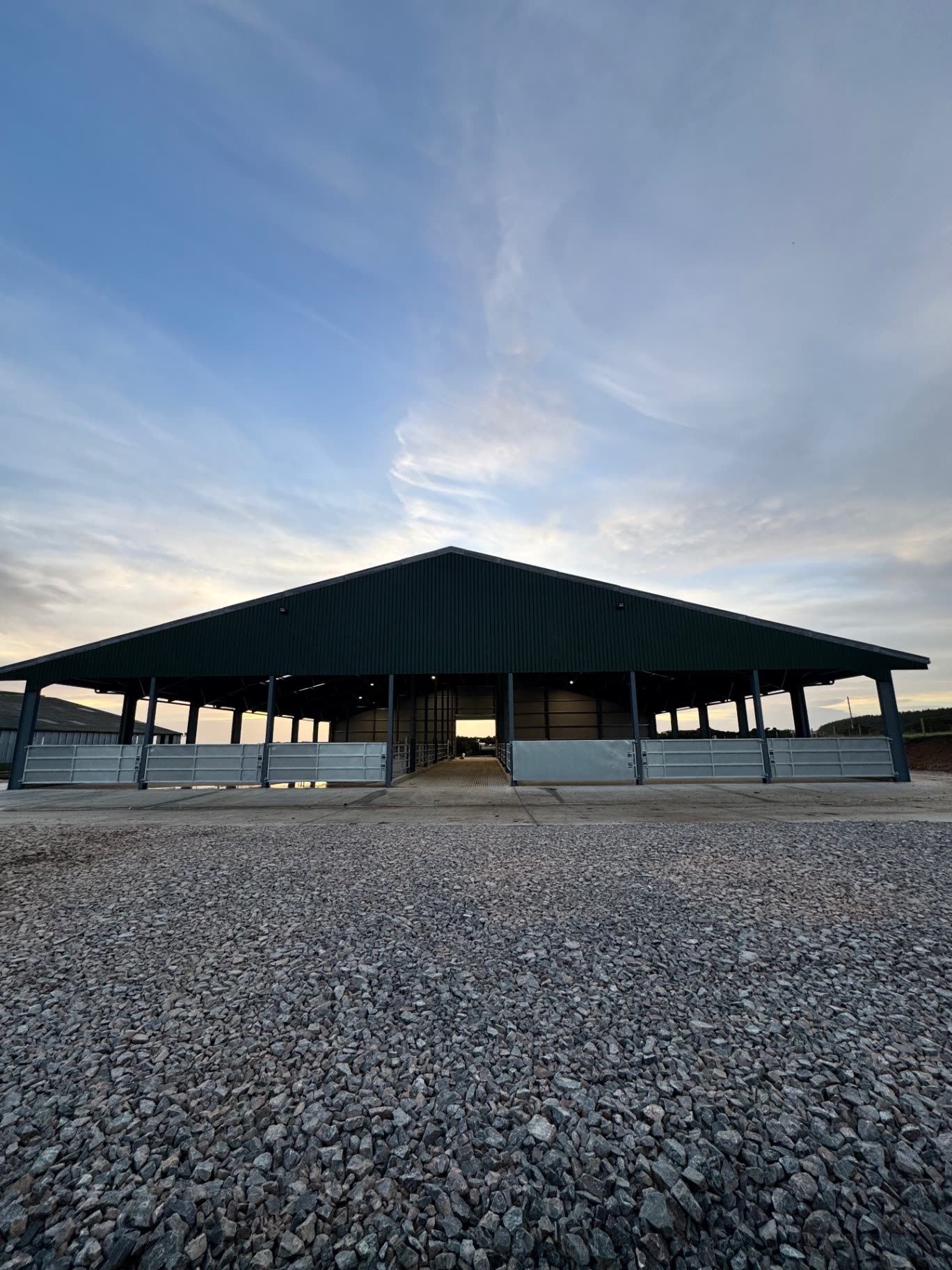 Front view of the cattle handling building at sunset with symmetrical open bays and concrete apron