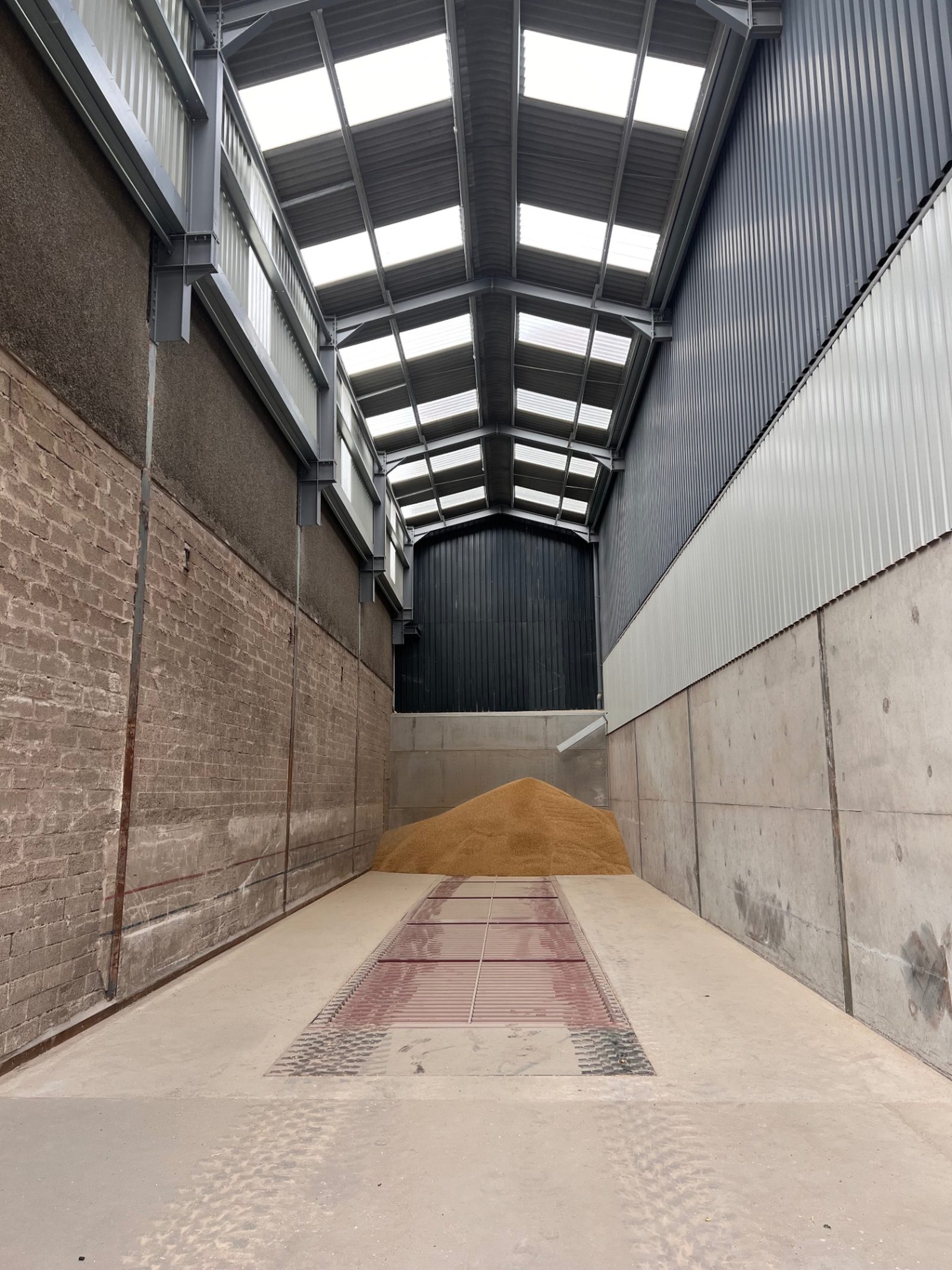 Wide interior view of the grain storage building with concrete walls and open working floor